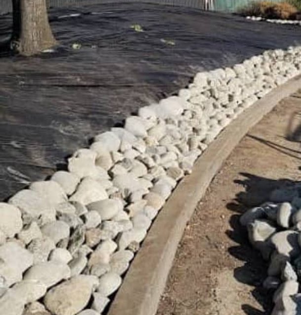 Rock border installation alongside fresh mulch and dirt